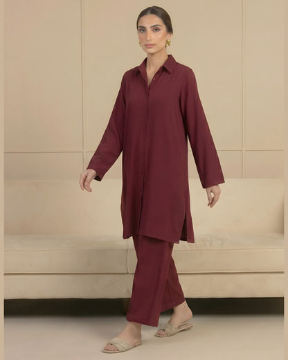 Woman wearing a burgundy outfit standing in a room with beige walls and furniture.