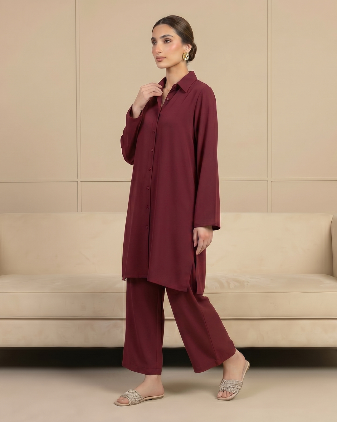 Woman wearing a burgundy outfit standing in front of a beige wall.